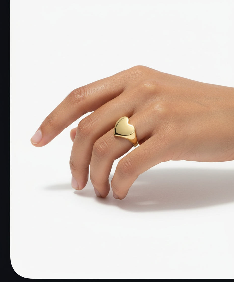 Heart-shaped gold ring on a hand with a matching necklace.