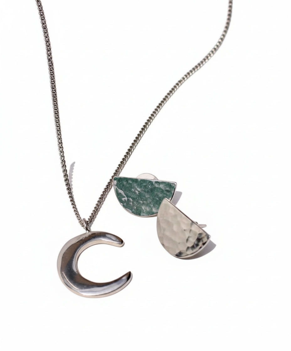 Necklace with a crescent moon pendant and green stone on an open book